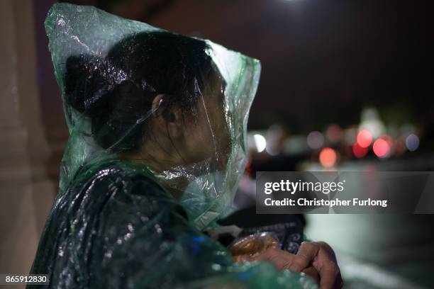 People take cover from torrential rain as they begin to queue and sleep on the streets overnight to attend Thailand's late King Bhumibol Adulyadej's...