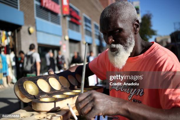 Jawarah, a citizen of Antigua works on Wari game, popular in the Caribbean and West Africa, on 125th street of Harlem neighborhood of New York City,...