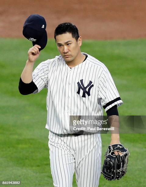 Pitcher Masahiro Tanaka of the New York Yankees tips his cap to the crowd as he leaves the field after pitching in the third inning of game 5 of the...