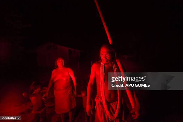 Chieftain Akaupotyr Waiapi walks with his family holding a flute, at night in the Manilha village in Waiapi indigenous reserve in Amapa state in...