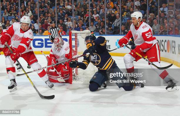 Justin Bailey of the Buffalo Sabres battles Dylan Larkin and Mike Green of the Detroit Red Wings in the offensive zone during an NHL game on October...