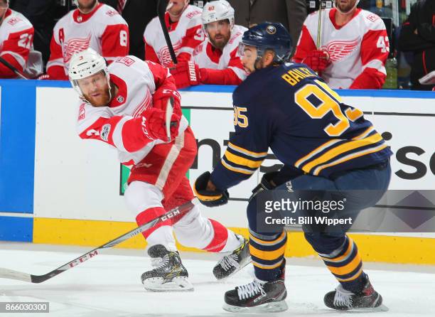 Nick Jensen of the Detroit Red Wings shoots the puck while Justin Bailey of the Buffalo Sabres defends during an NHL game on October 24, 2017 at...
