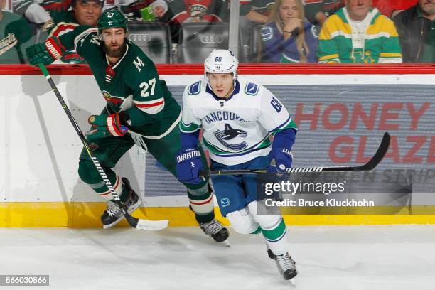 Markus Granlund of the Vancouver Canucks and Kyle Quincey of the Minnesota Wild skate to the puck during the game at the Xcel Energy Center on...