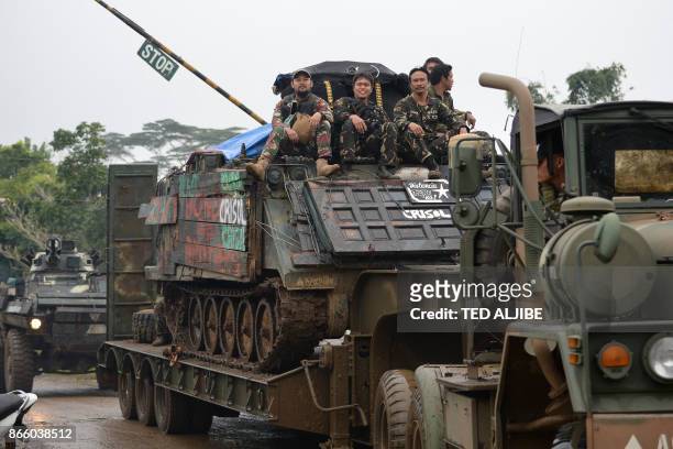 Philippine troops who fought against IS-inspired Muslim militants ride atop their armored personnel carrier loaded on a truck as they make their way...