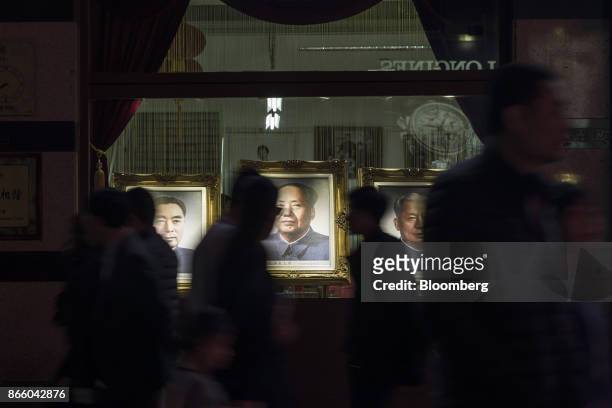 Pedestrians walk past portraits of former Chinese leaders Zhou Enlai, left, Mao Zedong, center, and Liu Shaoqi displayed in the window of a store on...
