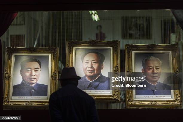 Pedestrian looks at portraits of former Chinese leaders Zhou Enlai, left, Mao Zedong, center, and Liu Shaoqi displayed in the window of a store on...