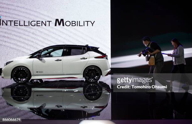 Members of the media look at Nissan Motor Co.'s Leaf NISMO Concept vehicle displayed during the Tokyo Motor Show at Tokyo Big Sight on October 25,...