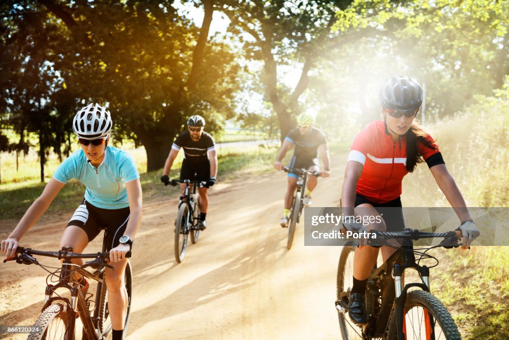 Determined cyclists riding bicycles on dirt road