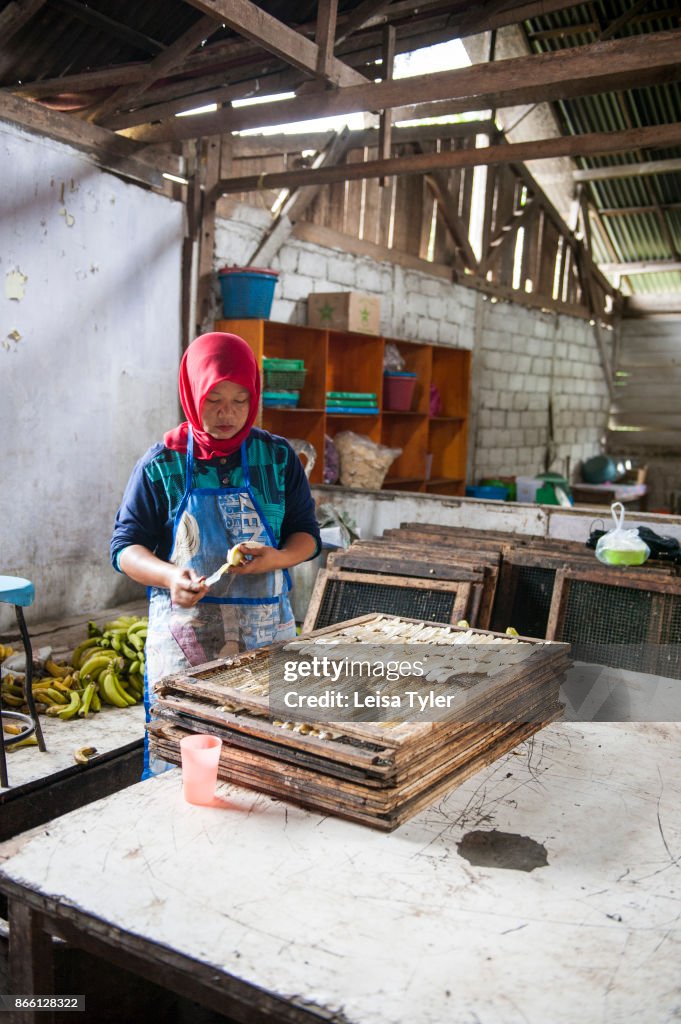 A lady prepares dried banana for selling in an adjacent shop...
