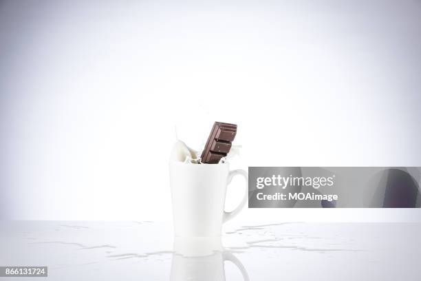 a piece of chocolate splashing in the cup of milk - chocolate milk splash stock pictures, royalty-free photos & images