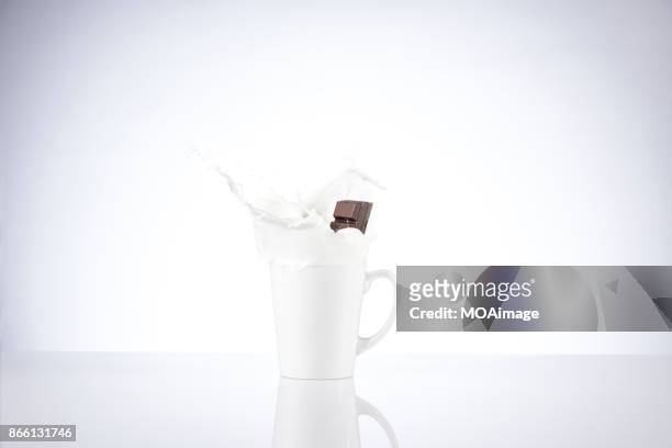 a piece of chocolate splashing in the cup of milk - chocolate milk splash stock pictures, royalty-free photos & images