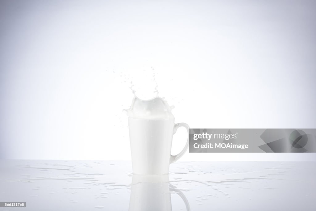 A piece of chocolate splashing in the cup of milk