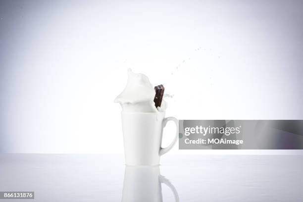 a piece of chocolate splashing in the cup of milk - chocolate milk splash stock pictures, royalty-free photos & images