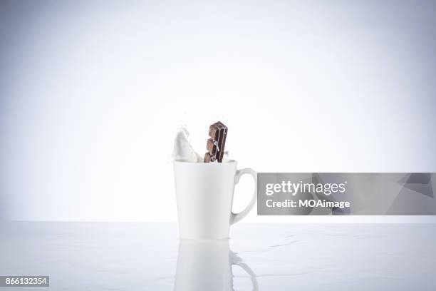 a piece of chocolate splashing in the cup of milk - chocolate milk splash stock pictures, royalty-free photos & images