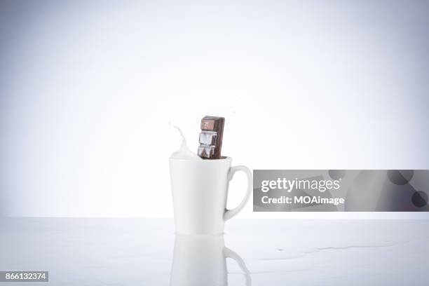 a piece of chocolate splashing in the cup of milk - chocolate milk splash stock pictures, royalty-free photos & images