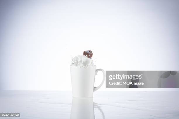 a piece of chocolate splashing in the cup of milk - chocolate milk splash stock pictures, royalty-free photos & images