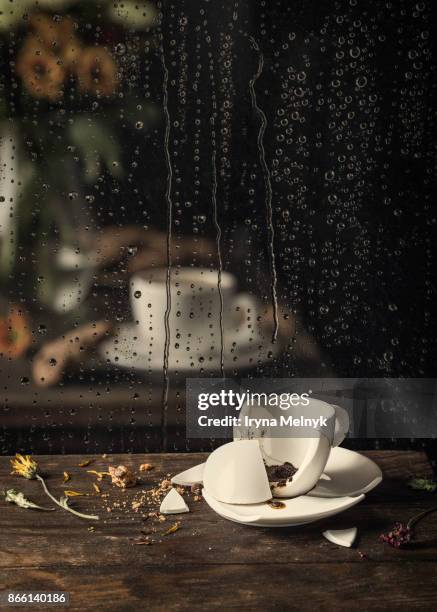 broken coffee cup and reflection in a rainy window glass - broken cup stock-fotos und bilder