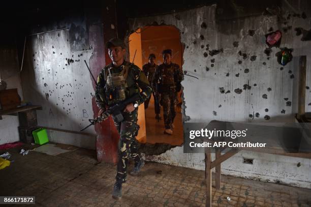 Government troops walk through a hole inside a bullet-riddled wall of a house in what was the main battle area in Marawi on the southern island of...