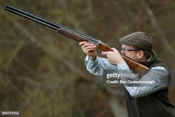 a man aiming a shot gun at clay pigeons - clay shooting stockfoto's en -beelden