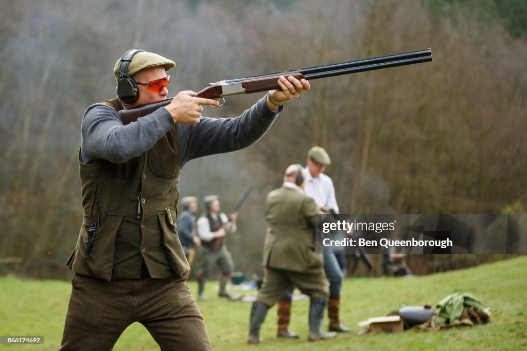 A man aiming a shot gun at clay pigeons