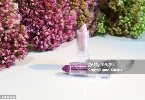 pink and purple lipsticks with flowers in the background - lila lippenstift stock-fotos und bilder