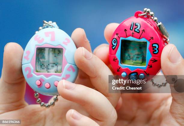 Children show their "Tamagotchi" electronic pet on October 25, 2017 in Paris, France. Tamagotchi is a virtual electronic animal which means "cute...