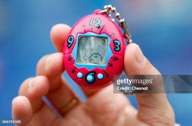 Child shows a "Tamagotchi" electronic pet on October 25, 2017 in Paris, France. Tamagotchi is a virtual electronic animal which means "cute little...