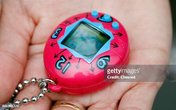 Child shows a "Tamagotchi" electronic pet toy on October 25, 2017 in Paris, France. Tamagotchi is a virtual electronic animal which means "cute...