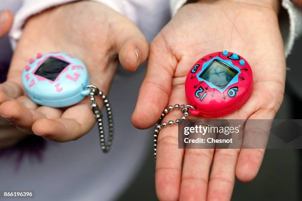 Children show their "Tamagotchi" electronic pet toy on October 25, 2017 in Paris, France. Tamagotchi is a virtual electronic animal which means "cute...