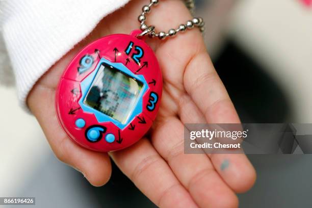 Child shows a "Tamagotchi" electronic pet toy on October 25, 2017 in Paris, France. Tamagotchi is a virtual electronic animal which means "cute...