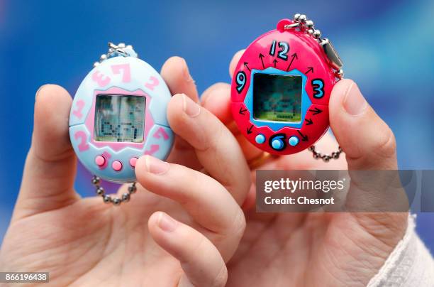 Children show their "Tamagotchi" electronic pet on October 25, 2017 in Paris, France. Tamagotchi is a virtual electronic animal which means "cute...