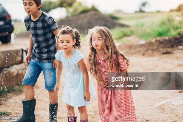 group of cute kids spitting water outdoors - saliva stock pictures, royalty-free photos & images