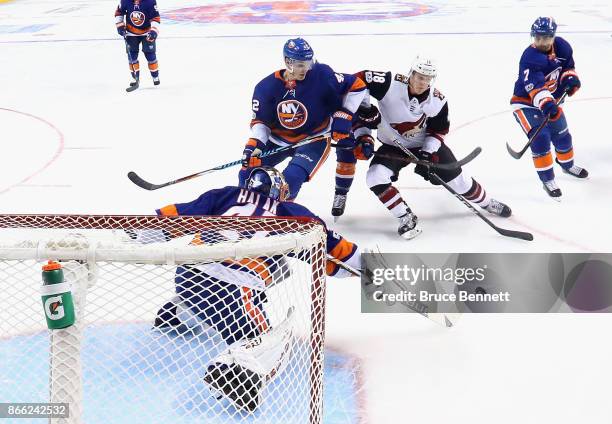 Jaroslav Halak of the New York Islanders sweeps the puck away from Christian Dvorak of the Arizona Coyotes at the Barclays Center on October 24, 2017...