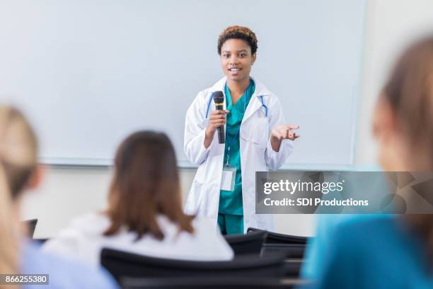 young female physician teaches a class at a medical school - doctor speech stock pictures, royalty-free photos & images