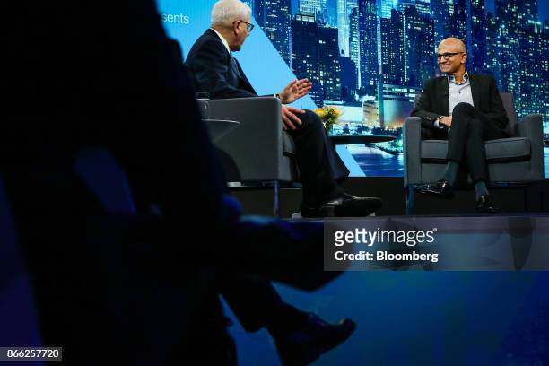 Satya Nadella, chief executive officer of Microsoft Corp., right, listens as David Rubenstein, co-chief executive officer of the Carlyle Group LP,...