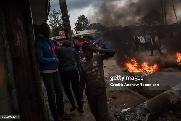 People walk by a burning roadblock lit protest for opposition presidential candidate Raila Odinga, in the Kibera slum, on October 25, 2017 in...