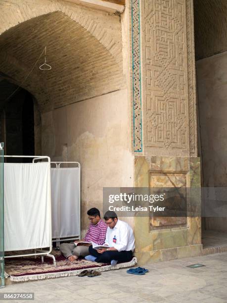 Two men reading inside the Masjed-e Jame in Esfahan, the oldest Friday mosque in Iran. The mosque is a good example of the evolution of Iranian...