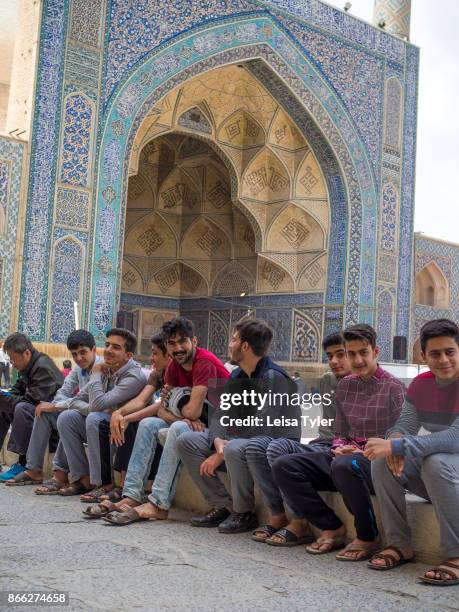 Young men sitting in the courtyard of the Masjed-e Jame in Esfahan, the oldest Friday mosque in Iran. The mosque is a good example of the evolution...