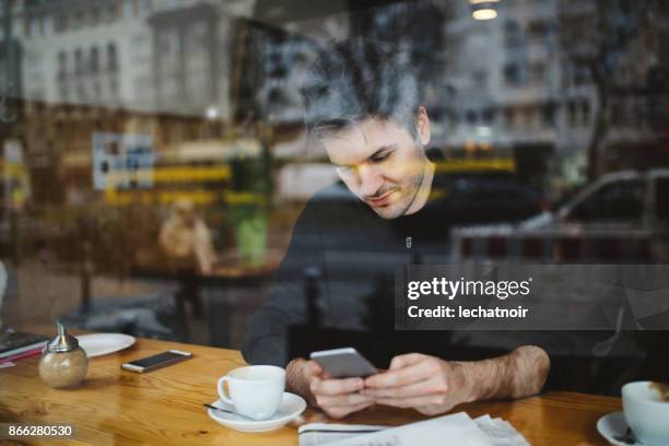 giovane che si rilassa in un bar di berlino, sms al cellulare - coffee and news paper foto e immagini stock