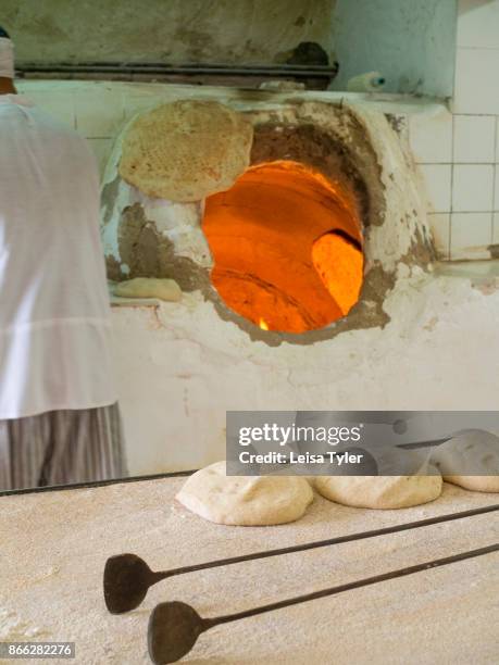 Baking naan bread in a traditional wood fired oven, known as a tandoori, in Aqda, Iran.