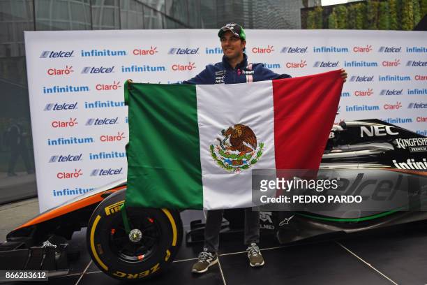 Sahara India Force Mexican driver Sergio "Checo" Perez poses for pictures holding his national flag after a press conference in Mexico City, on...