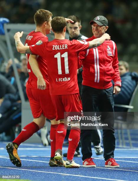 Simon Zoller of Koeln jubilates with team mates and head coach Peter Stoeger after scoring the first goal during the DFB Cup match between Hertha BSC...