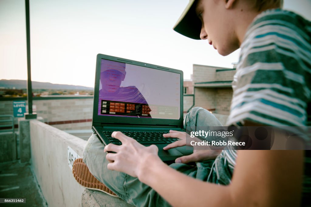 A teenage boy hacking with a laptop computer to commit cyber crime