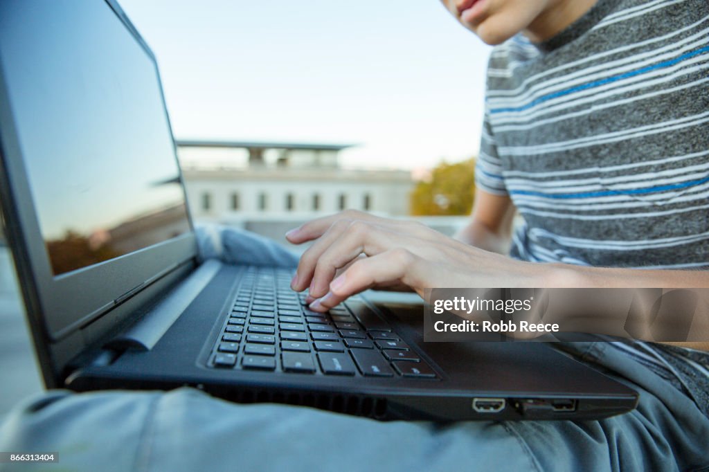 A teenage boy hacking with a laptop computer to commit cyber crime