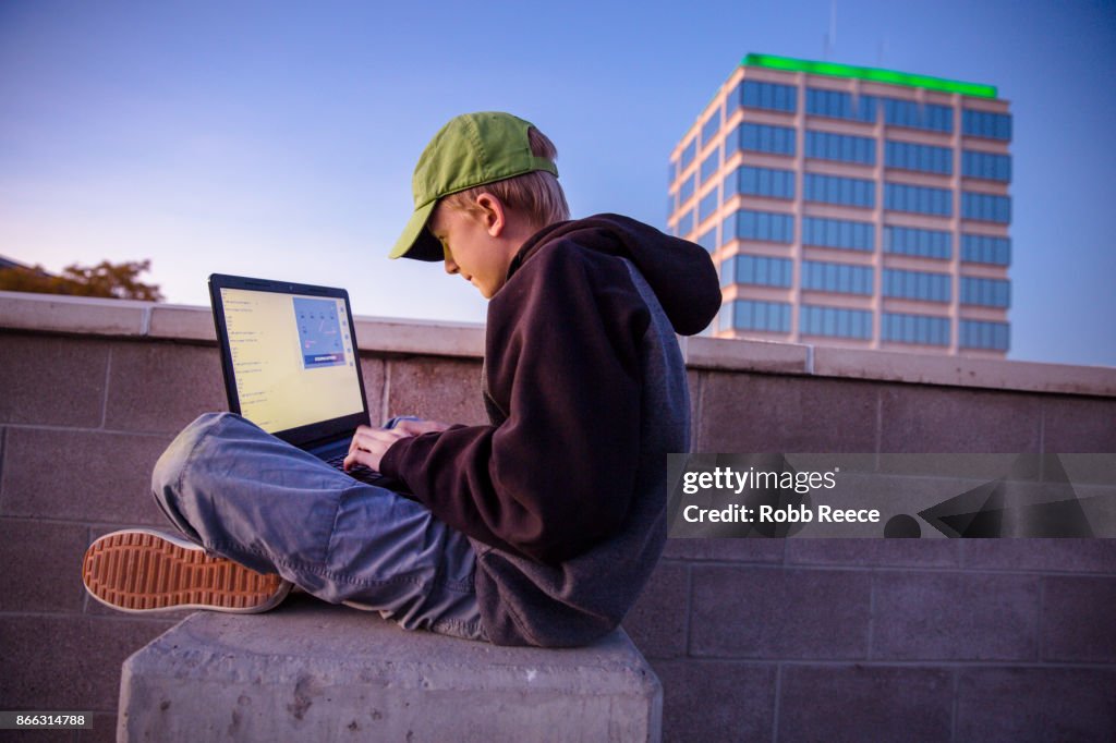 A teenage boy hacking with a laptop computer to commit cyber crime