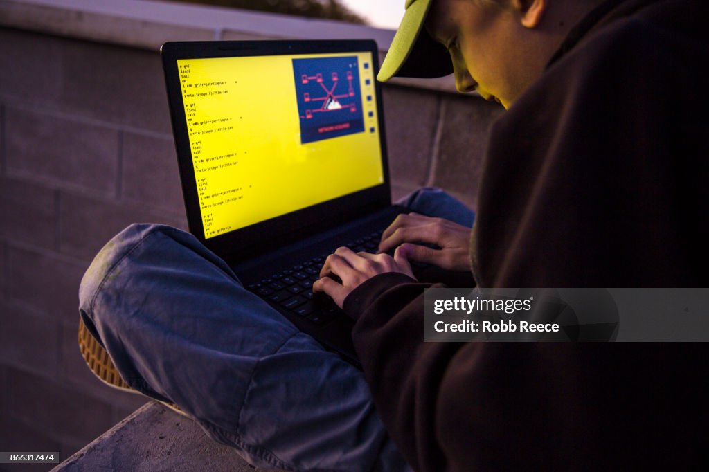 A teenage boy hacking with a laptop computer to commit cyber crime