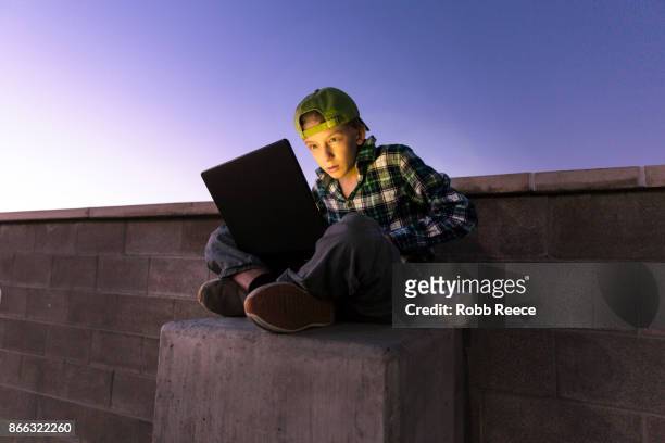 a teenage boy hacking with a laptop computer to commit cyber crime - robb reece stockfoto's en -beelden
