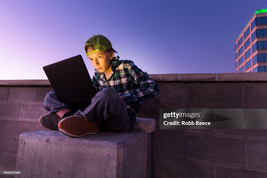 A teenage boy hacking with a laptop computer to commit cyber crime