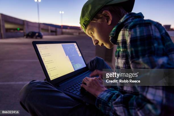 a teenage boy hacking with a laptop computer to commit cyber crime - robb reece stock-fotos und bilder