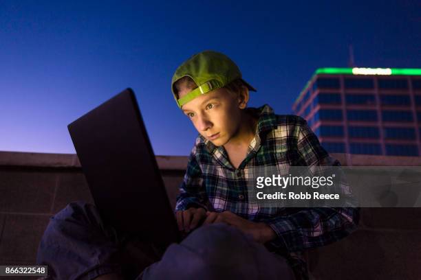a teenage boy hacking with a laptop computer to commit cyber crime - robb reece stockfoto's en -beelden